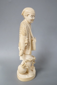 A Japanese carved ivory figure of a farmer, Meiji period, c.1900, signed, carrying a lantern on a stick, maize grows at his feet, a toad climbs on one arm, height 20.5cm